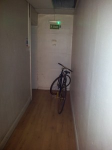 A bicycle left in a hallway obstructing the fire exit door.